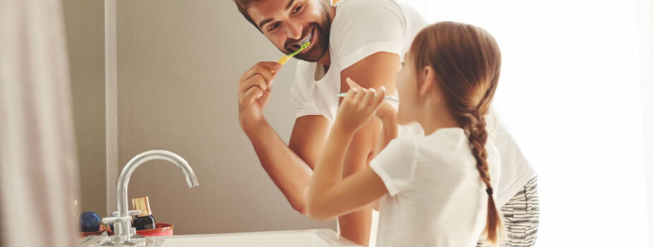 Un père et sa fille se brossent les dents dans leur salle de bain.
