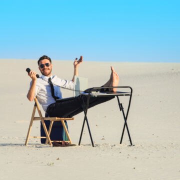 Employé heureux avec son bureau dans le désert pour montrer l'importance de l'espace de travail ergonomique. FReepik.