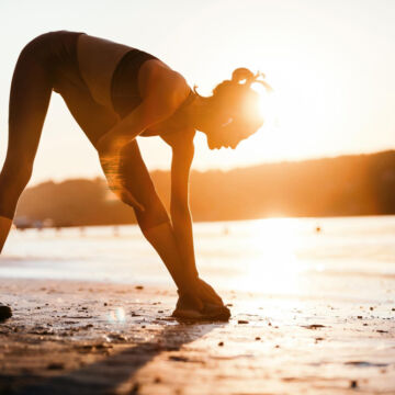 Jeune femme qui fait du sport sur la plage pour détendre ses articulations et rester en bonne santé.