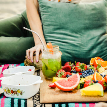 Pique nique et femme qui mange des fruits et légumes crus sur une nappe.