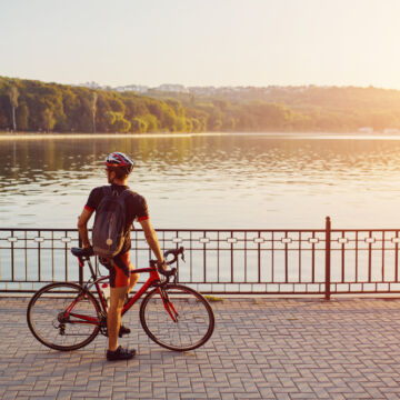 Personne qui fait du vélo pour rester en bonne santé, au bord d'un lac avec du soleil.