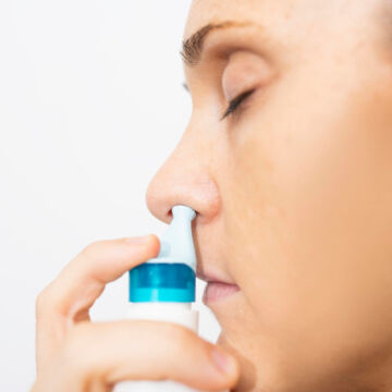 Femme qui utilise une solution nasale pour faciliter l'écoulement du mucus et soigner sa sinusite.