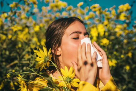 Jeune femme avec une sinusite dans un champ de fleurs.