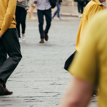 Personnes qui marchent dans la rue et portent des vêtements jaunes.
