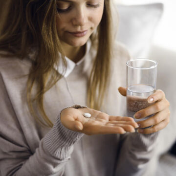 Femme qui prend un antidépresseur prescrit par un psychiatre et remboursé par l'Assurance Maladie. Médicament sous forme de pilule blanche à avaler avec de l'eau.