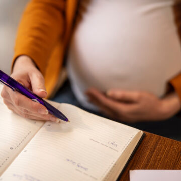 Femme enceinte après une procréation médicalement assistée qui note ses rendez-vous médicaux dans son agenda.