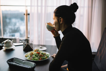 Jeune femme qui boit un café et déjeune, elle souffre de troubles du comportement alimentaire (TCA).