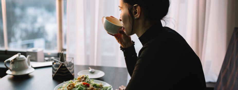 Jeune femme qui boit un café et déjeune, elle souffre de troubles du comportement alimentaire (TCA).