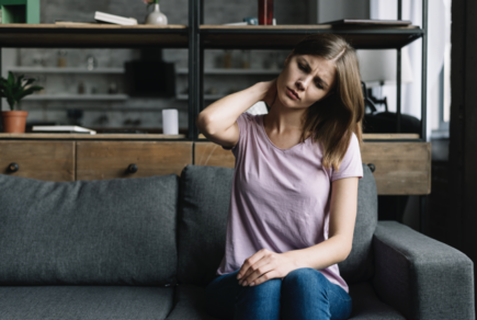 femme assise sur un sofa avec une douleur au cou