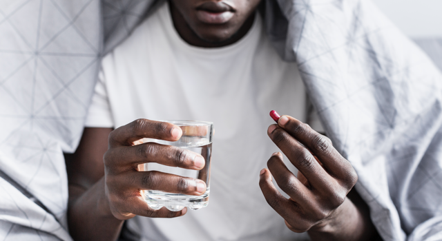 homme tenant un médicament et verre d'eau à la main